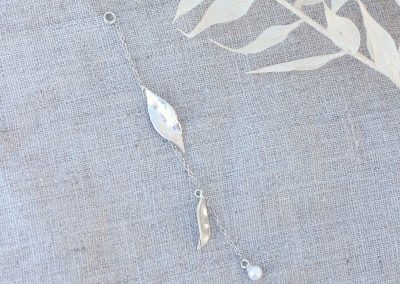 lang tillægskæde i sølv med blomsterblade hængende og en hvid ferskvandsperle for enden