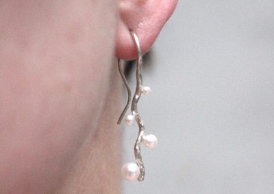 bølgende ørebøjler i sølv med perler på model